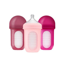 Boon Nursh 8oz baby bottles in pink and purple tones, featuring a silicone sleeve and clear measurement markings.