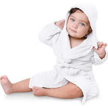 White muslin bathrobe for toddlers, featuring a hood, worn by a seated baby with curly hair and blue eyes.