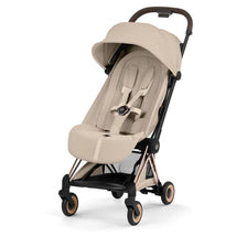 Cybex Platinum Coya Stroller with a rose gold frame and cozy beige seat, featuring a collapsible design and safety harness.
