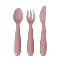 Blush-colored set of three utensils: a spoon, fork, and knife, designed for young children.