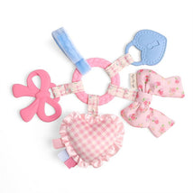 Teething activity toy featuring a pink heart, floral bows, silicone rings, and a textured handle for sensory play.