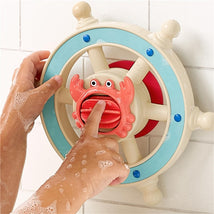 Colorful crab-shaped bath steering wheel toy with textured surface; a child’s soapy hands are engaging with it.