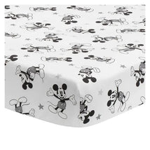 Fitted crib sheet featuring a playful black and white Mickey Mouse pattern with scattered stars.
