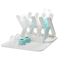 Munchkin Bottle Drying Rack and Mat in white, holding several baby bottles, lids, and parts on a ribbed mat.