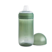 Mushie Soft Spout Sippy Cup in Dried Thyme color, featuring a clear body, measurement markings, and a removable lid.