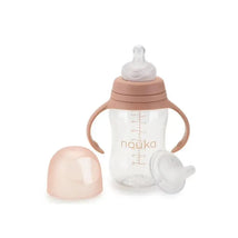 Transitional baby bottle/sippy cup in soft blush, featuring handles, measurement markings, and interchangeable tops.
