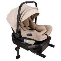 Nuna PIPA™ aire Infant Car Seat in Biscotti color, securely attached to the PIPA™ Series Base, featuring a protective canopy and safety labels.