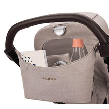 Nuna Stroller Organizer in Biscotti color, featuring a pocket with a water bottle, notebook, and a teething toy.