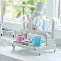 Gray drying rack holding colorful cups and lids, showcasing its use for drying dishes efficiently.