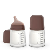 Suavinex 2-pack anti-colic baby bottles in deep tone with adaptable flow nipples, featuring measurement markings on the side.
