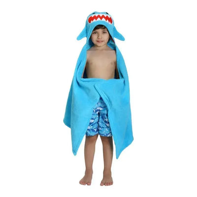 Child wearing a blue Zoocchini Sherman the Shark Hooded Towel with shark features, standing barefoot, and wearing shark-patterned swim trunks.
