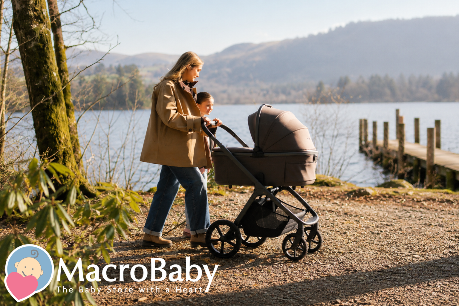 Mom pushing baby stroller by lake with child walking beside, scenic outdoor family moment