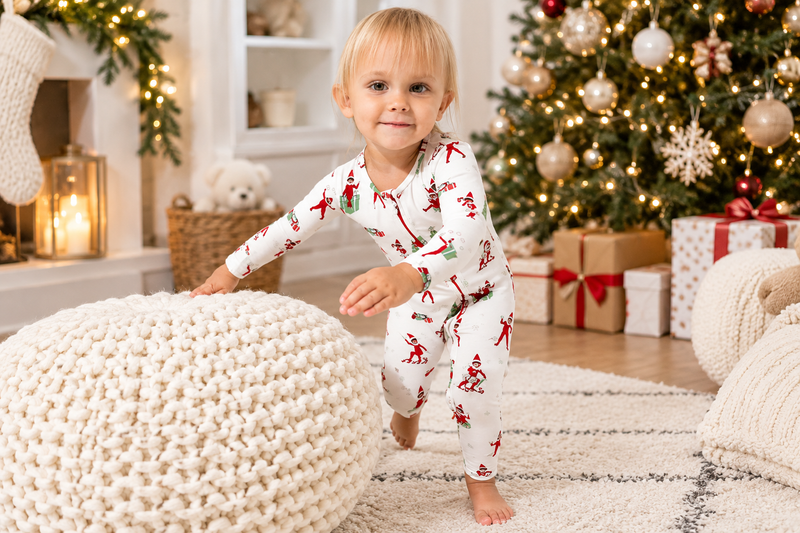 Toddler wearing Christmas pajamas beside a decorated Christmas tree.