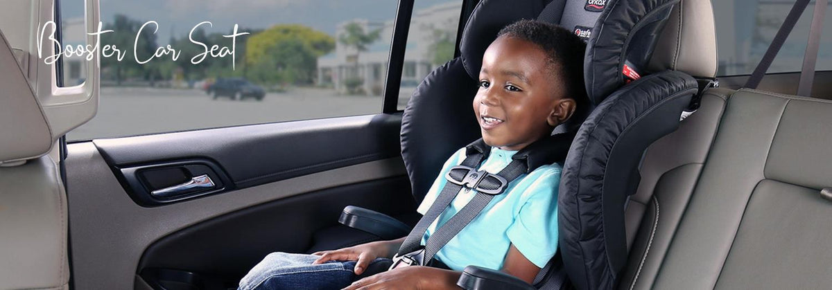 Child smiling in black booster car seat with harness, safely secured in vehicle backseat