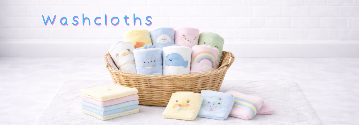 Soft baby washcloths with cute animal and rainbow designs, neatly folded in a wicker basket and on a towel.