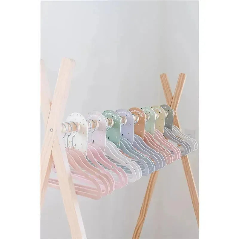 Cream colored baby velvet hangers in assorted pastel shades, organized neatly on a wooden rack.