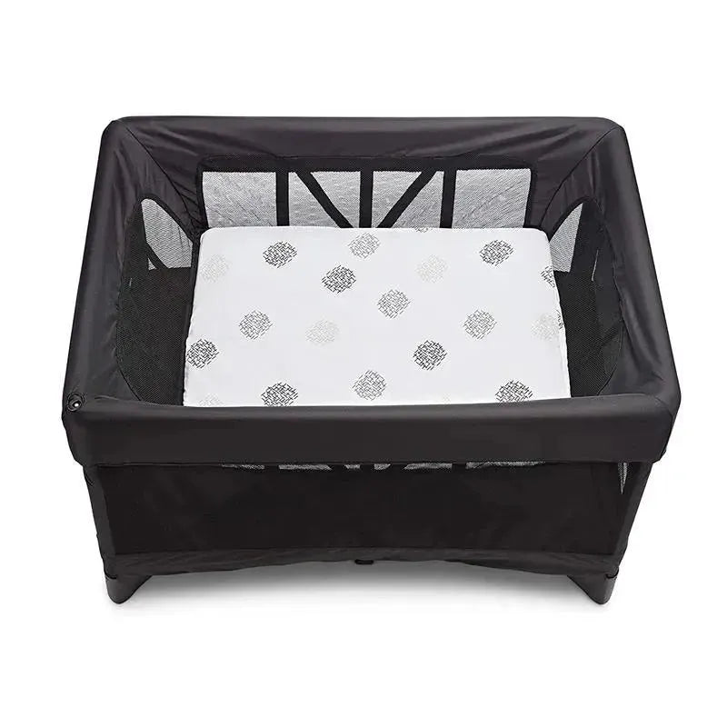 Breeze bassinet with a white, patterned mattress inside a black mesh frame, designed for infants.