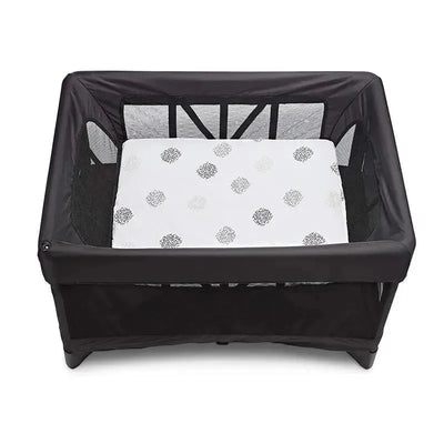 Breeze bassinet with a white, patterned mattress inside a black mesh frame, designed for infants.