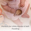 Baby in a pink outfit holding a Primo Passi rose pink snack cup filled with cereal.