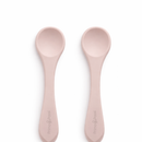 Two Primo Passi rose pink silicone baby feeding spoons on a white background.