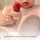 Baby using a Primo Passi rose pink silicone food feeder with a fresh strawberry.