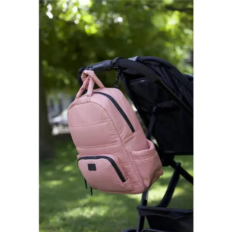 Diaper backpack in Rose Dawn color, hanging from a stroller, featuring side zip pockets and a quilted design.