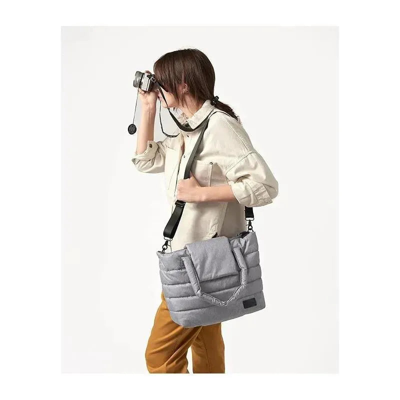 Woman in a beige shirt holding a camera, carrying a heather grey 7AM Voyage Capri Diaper Bag Tote.