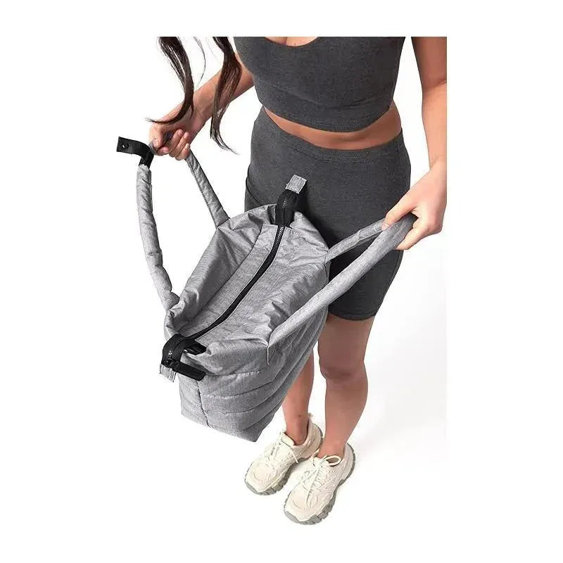 Heather grey Capri diaper bag tote with adjustable straps, held by a person in activewear.