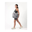 Woman in a black tank top and shorts carries a heather grey 7AM Voyage Capri Diaper Bag Tote with a shoulder strap.