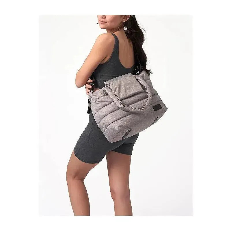 Heather grey 7AM Voyage Capri diaper bag tote being carried by a woman wearing a dark outfit, showcasing its design.