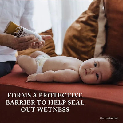 A+D Original Diaper Rash Ointment is applied to a baby lying on a couch, promoting a protective barrier against wetness.