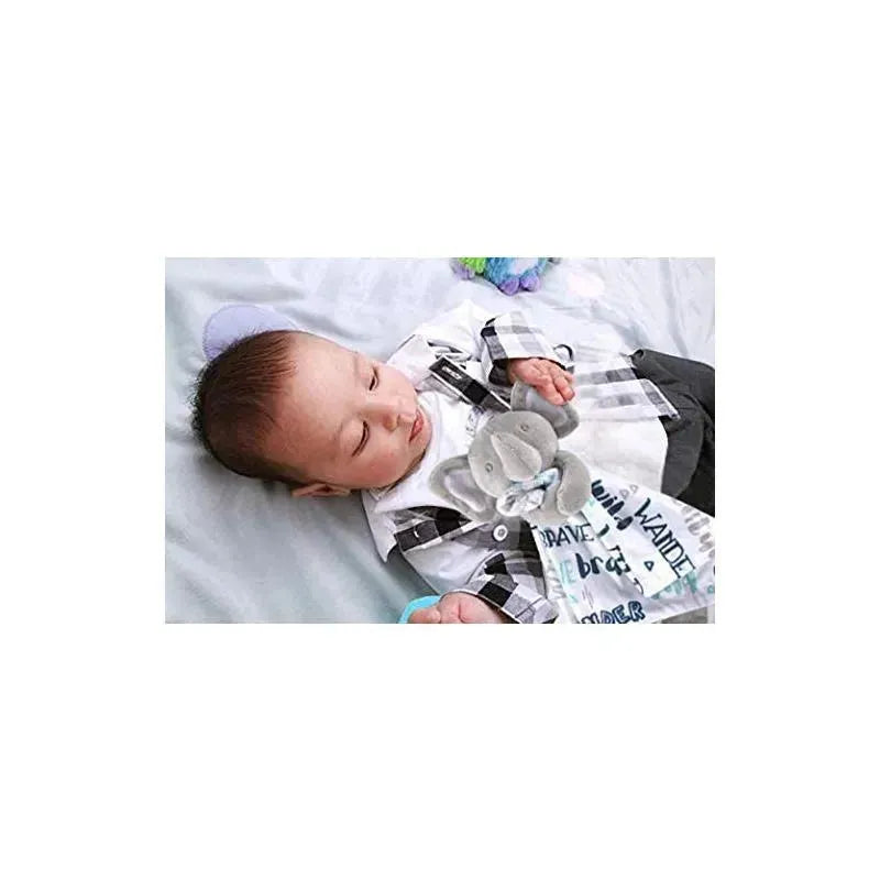 Baby is peacefully sleeping on a soft surface, holding a security blanket with an elephant design.