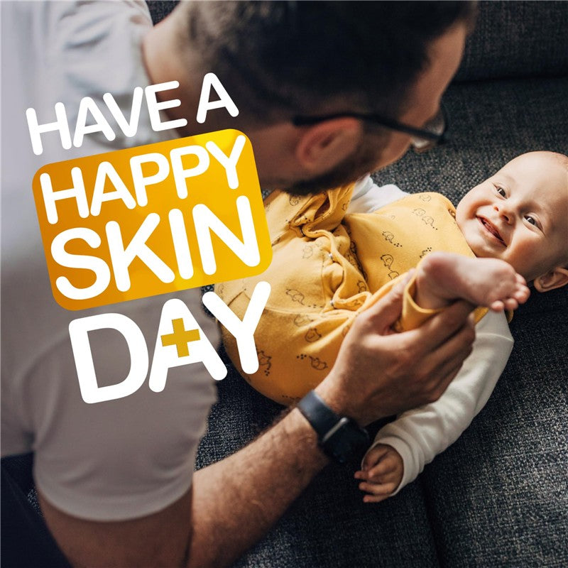 Father playfully interacting with a smiling baby on a couch, with text promoting happy skin care.