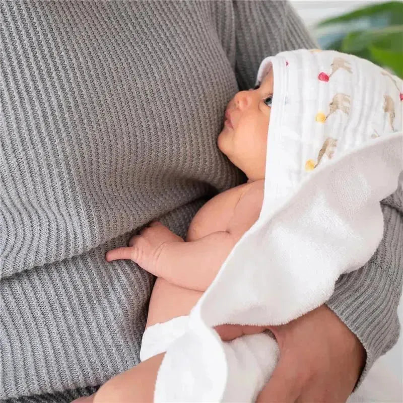 Hooded baby bath towel with elephant design draped over a newborn held by a person wearing a gray sweater.