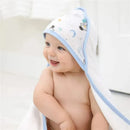 Hooded baby bath towel featuring a space explorer design; a smiling baby is wrapped in the towel, showcasing its playful style.