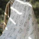 Silky soft swaddle featuring a floral design, part of the Aden + Anais 3-Pack, draped over a chair.