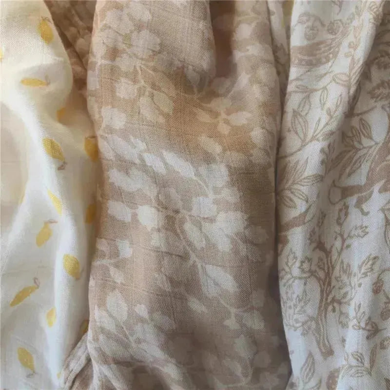 Three Aden + Anais swaddles featuring soft, natural fabrics with woodland-themed designs in neutral colors.