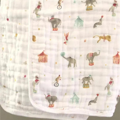 Circus-themed baby blanket featuring playful elephants, lions, and clowns on a white background.