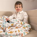 A child smiles while wrapped in an Aden + Anais Essentials Cotton Muslin Blanket featuring Toy Story characters and cactus designs.