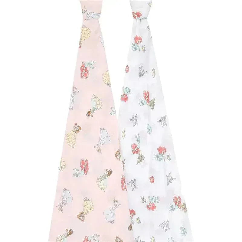 Two muslin swaddles featuring Disney Princess designs: one pink with princess illustrations, the other white with floral patterns.