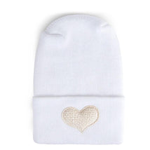 Fuzzy ivory hospital hat for babies with a heart-shaped embroidery on the cuff. Perfect for newborn gifting.