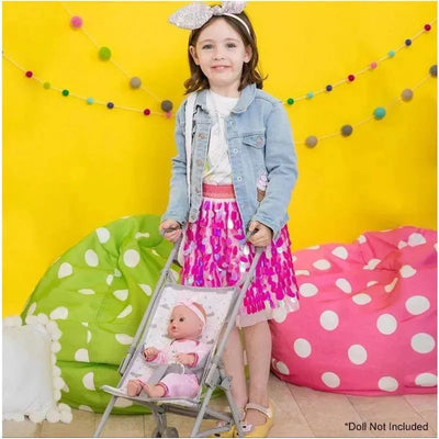 A girl in a pink and white skirt pushes a glittery baby doll stroller with a doll inside against a bright yellow background.