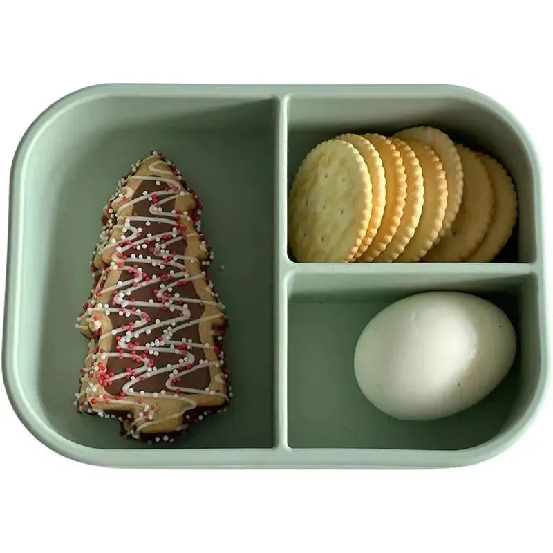 Leakproof silicone bento box in pine color with sections containing a decorated Christmas tree cookie, crackers, and a hard-boiled egg.