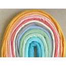 Ali + Oli Muslin Swaddle Blanket in Dream Blue, featuring a soft fabric with a pastel rainbow of colors arranged in layers.