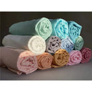 Muslin swaddle blankets in various soft colors, neatly rolled and stacked for display.