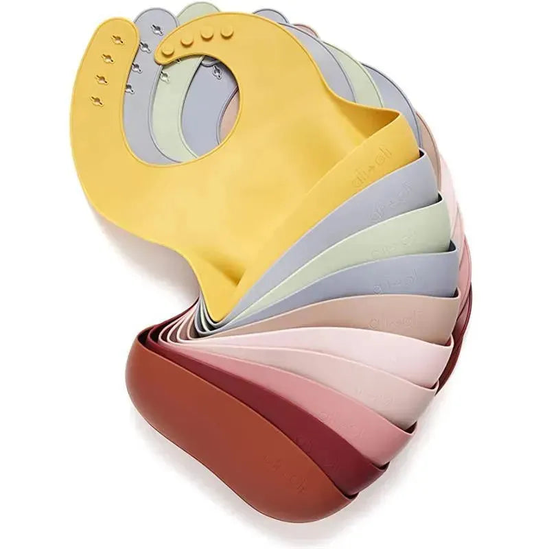Silicone baby bibs in various colors, including light sage, designed for easy cleaning and roll-up storage.