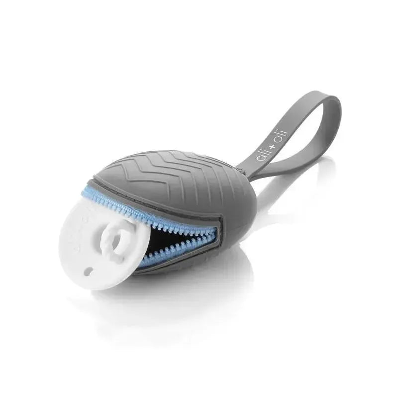 Grey Ali+Oli silicone pacifier case with blue zipper, partially open to reveal a white pacifier inside.