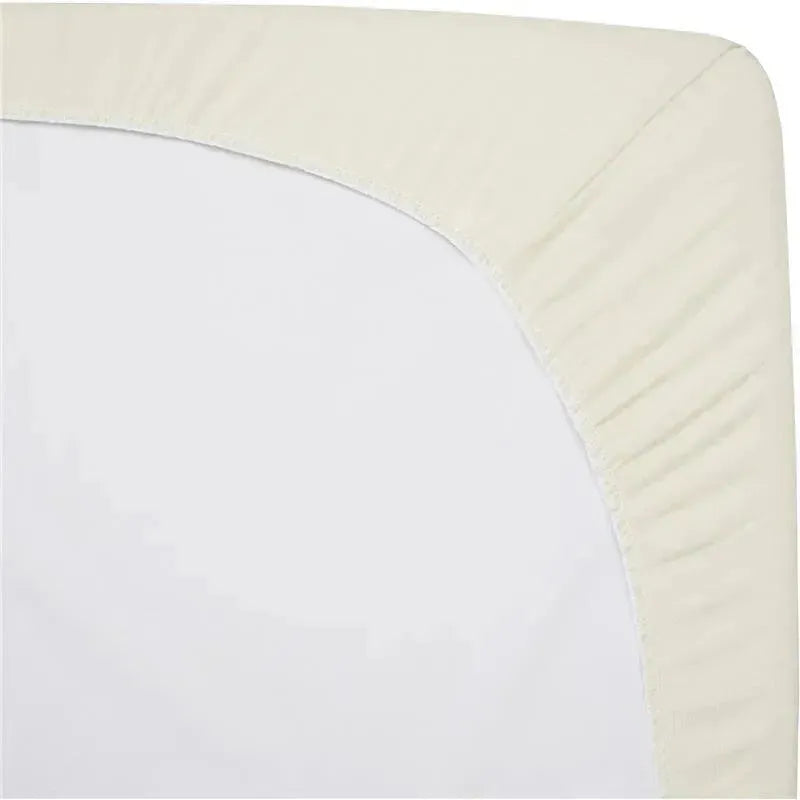 Cream-colored fitted bassinet sheet made of 100% natural cotton jersey knit, neatly wrapped around a mattress corner.