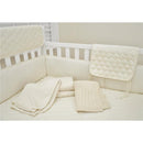 Thermal/waffle swaddle blanket made with organic cotton in natural color laid in a crib, alongside other soft, cream-colored bedding.