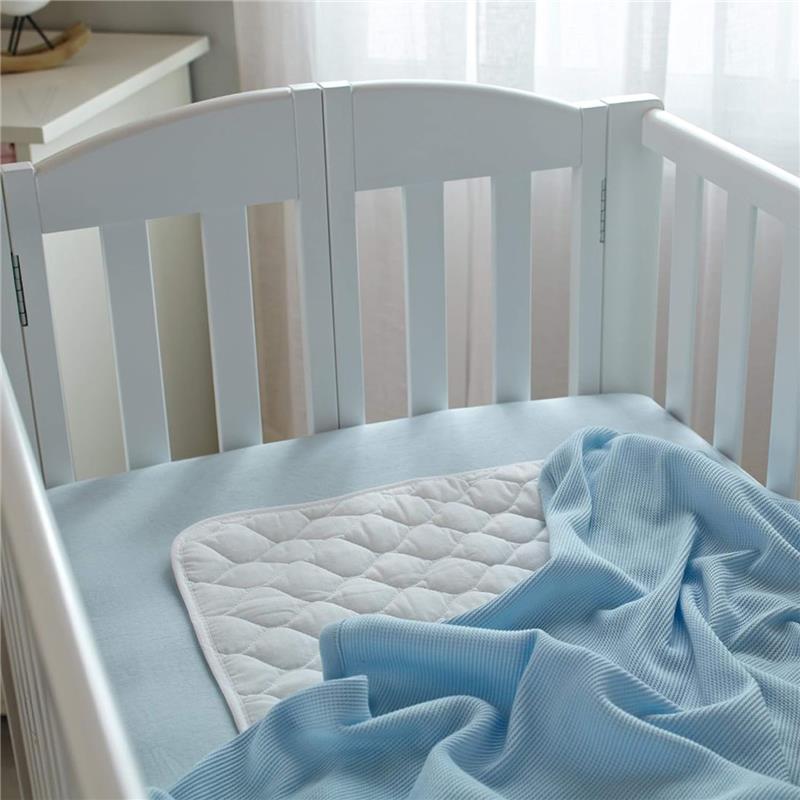 100% cotton thermal waffle swaddle blanket in blue, neatly draped over a crib mattress with a quilted mattress pad.